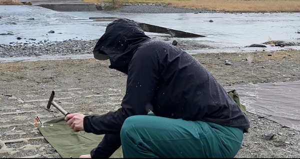 ミレーの防水透湿ジャケットを着て雨のなかキャンプの設営をする様子